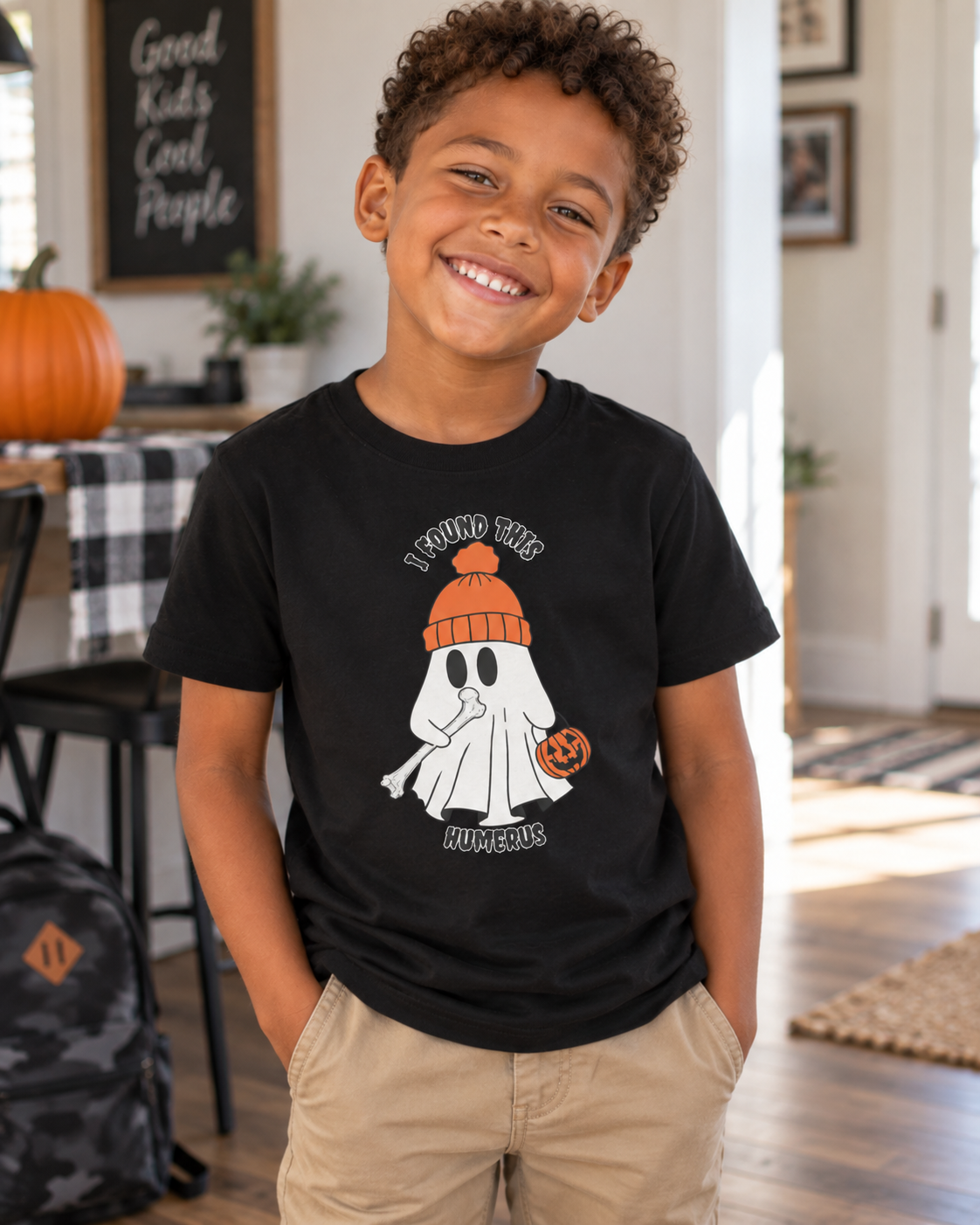 Boy wearing black youth t-shirt with ghost holding a bone and pumpkin bucket, text reads "I Found This Humerus" - funny medical Halloween tee